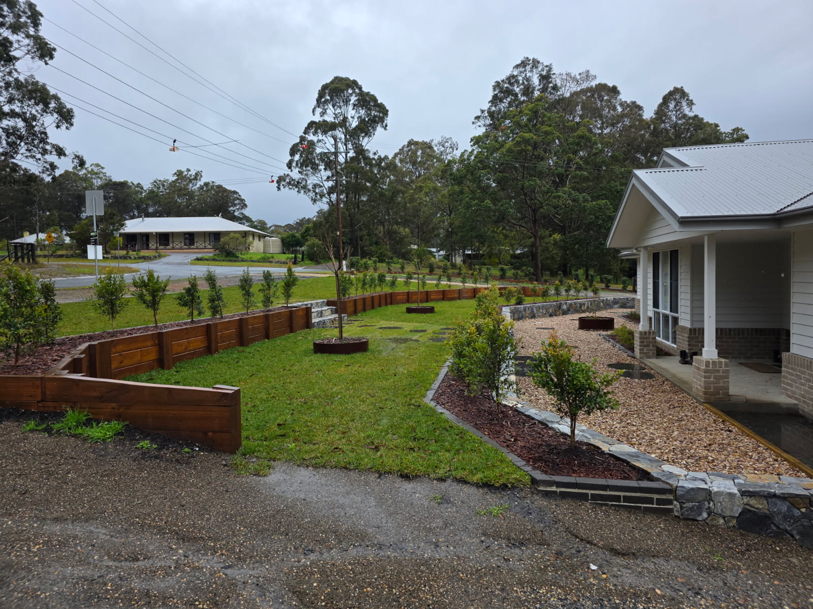 Timber retaining wall with feature trees and pebble beds